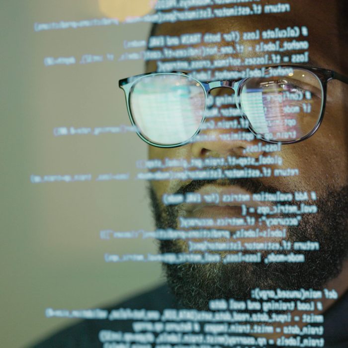 Stock photograph of an afro Caribbean (afro American) man studying a see through display depicting Python computer coding.